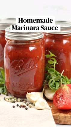 homemade marinara sauce in mason jars on a cutting board with fresh vegetables and herbs