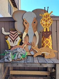 an elephant, giraffe, and zebra cutout on a wooden table outside