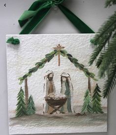 a nativity scene is hanging on the wall next to a pine tree and green ribbon