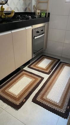 three rugs on the kitchen floor in front of an oven and dishwasher