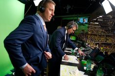 two men in suits and headphones standing at a desk