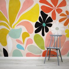 a chair sitting in front of a wall with flowers painted on it