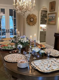 a dining room table filled with many plates and trays of food on top of it