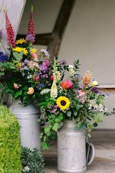 two vases filled with different types of flowers on the side of a building next to each other