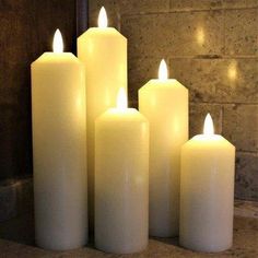 five lit candles sitting in front of a brick wall