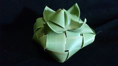 an origami flower made out of green paper on a black tablecloth background