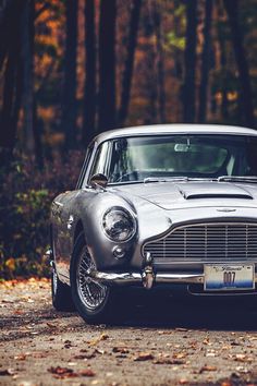 an old silver car parked in front of some trees