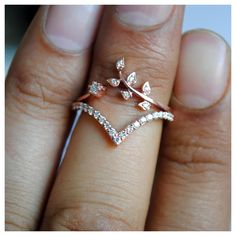 a close up of a person's hand holding a ring with leaves on it