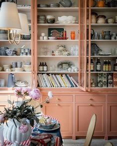 a dining room with pink cabinets and flowers on the table