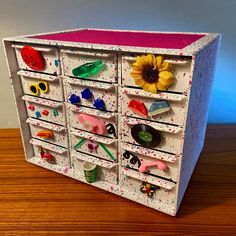 a wooden table topped with a drawer filled with lots of magnets and sunflower