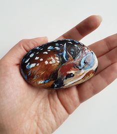 a hand holding a painted rock in it's palm