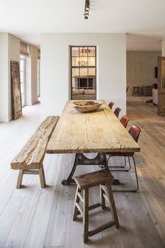 a large wooden table sitting in the middle of a room with chairs and a bowl on top of it