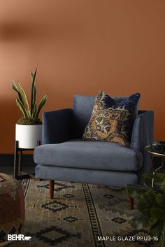 a blue chair sitting in front of a potted plant on top of a rug