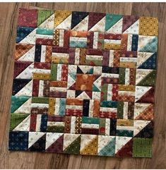 a quilted table topper on a wooden floor with an orange and green design