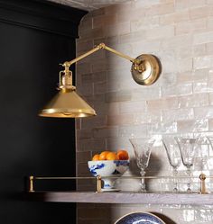 a table with plates and glasses on it next to a wall light that is gold