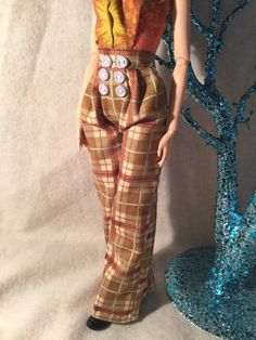 a doll is standing next to a blue and white tree with buttons on its pants