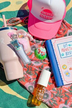 various items are laid out on a colorful blanket, including an ice cream container, and a pink hat