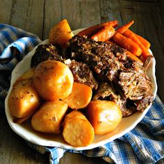 a white plate topped with roast, potatoes and carrots