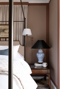 a bed sitting next to a lamp on top of a table