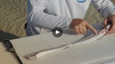 a man cutting up some fish on top of a surfboard