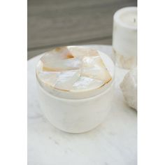 a white bowl sitting on top of a table next to a candle and some rocks