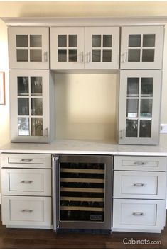 a wine cooler built into the side of a kitchen cabinet with glass doors and drawers