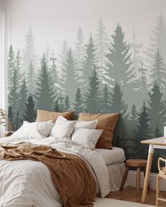 a bed sitting under a window next to a forest wall mural