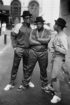 three men standing next to each other on the street