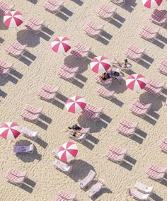 people are sitting on beach chairs and umbrellas in the sand, looking down at them