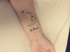 a woman's arm with a crescent moon tattoo on the left side of her wrist