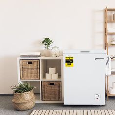 a white refrigerator sitting in the middle of a room next to baskets and toiletries