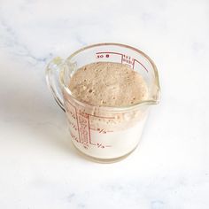 a glass measuring cup filled with oatmeal on top of a white counter