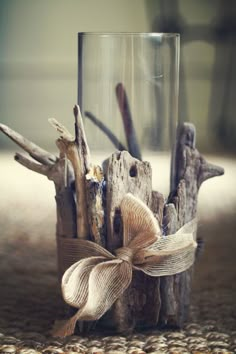 a glass vase filled with driftwood and a bow on the front, sitting on a table