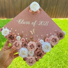 a hand holding up a graduation cap with flowers on the front and side, that says class of 2021