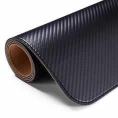 a roll of black and brown carbon fiber vinyl on a white background with an orange stripe