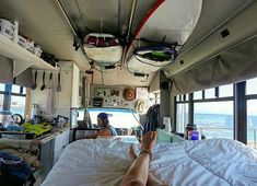 a person laying on top of a bed in a room next to a large window