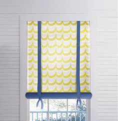 an open window with yellow and blue roman shades on the windowsill, in front of a white painted wall