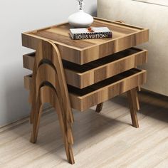 a small wooden table with three drawers on it and a white couch in the background