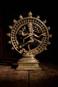 an intricately decorated brass statue on a wooden table in the dark with black background