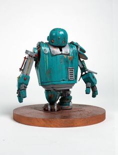 a blue robot standing on top of a wooden base