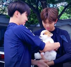 two boys are holding a small dog in their hands