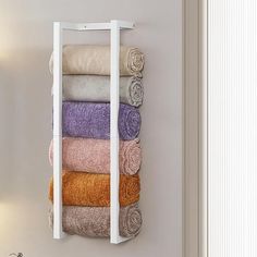 a towel rack with towels hanging from it's sides in a white room next to a wall