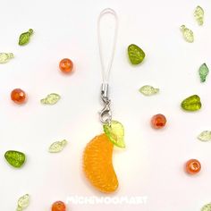 an orange shaped keychain with green leaves and gummy bears around it on a white surface