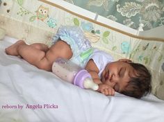 a baby laying on top of a bed with a bottle in it's mouth