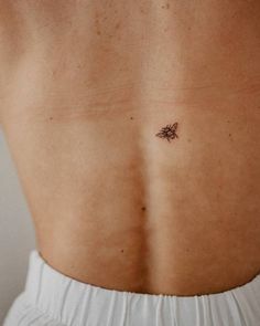 the back of a woman's stomach with a small tattoo on her left side