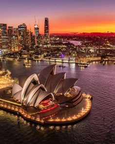 an aerial view of the sydney opera house at night, with city lights in the background