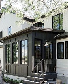 a small house with stairs leading to the front door and side windows on both sides