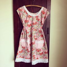 a pink and white dress hanging on a wooden hanger in front of a door