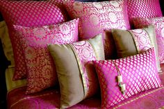 pink and gold pillows on a bed in a bedroom