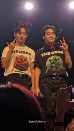 two young men standing on stage giving the peace sign